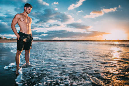 a young man exercises on the beach at sunset on a beach. Warm colorsの写真素材