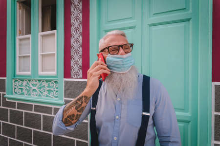 an older man in hipster clothes and glasses and a long white beard use the mobile phone focus on...