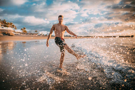a young man exercises on the beach at sunset on a beach. Warm colorsの写真素材