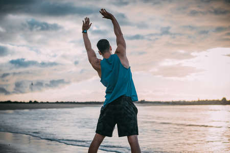 a young man exercises on the beach at sunset on a beach. Warm colorsの写真素材