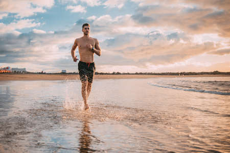 a young man exercises on the beach at sunset on a beach. Warm colorsの写真素材