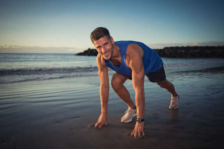 a young man exercises on the beach at sunset on a beachの写真素材