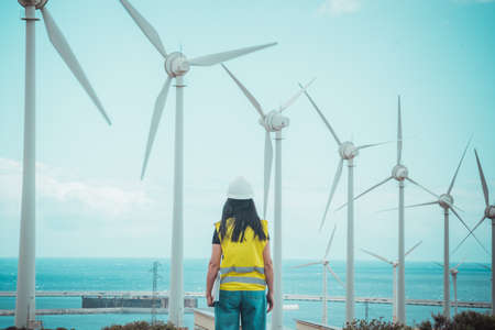 adult female engineer supervises solar panels and windmills in a renewable energy complexの写真素材