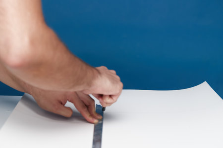 Anonymous person cutting a piece of cardboard with a box cutterの写真素材
