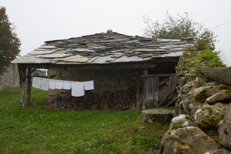 Old village house with slate roof and white linen hanging on the porch where the firewood is keptの写真素材