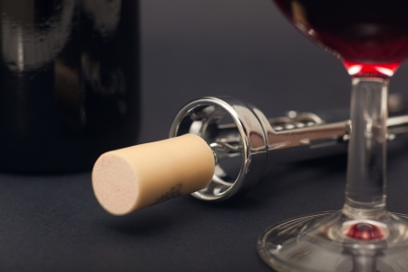 Glass, corkscrew and bottle of wine in black backgroundの写真素材