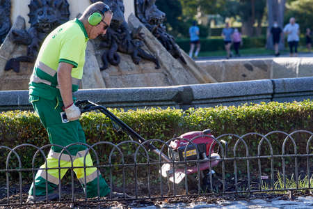 Madrid, Spain - May 27, 2020:  Gardener of the town hall with a short lawn machine.のeditorial素材