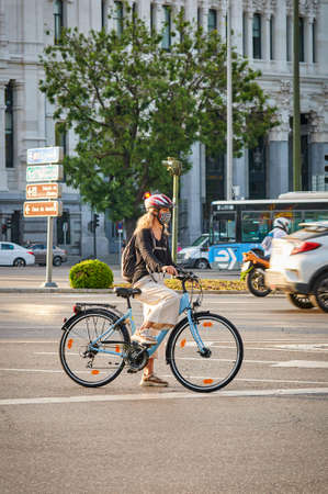 Madrid, Spain - May 25, 2020: A woman rides her bike to work and wears a mask to protect herself from the Covid-19のeditorial素材