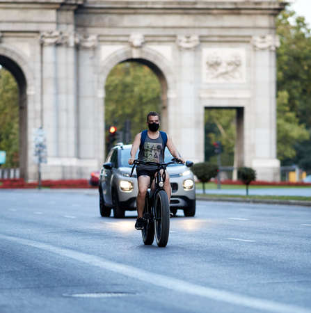Madrid, Spain - August 8, 2020: A rider her bike to work and wears a mask to protect herself from the Covid-19のeditorial素材