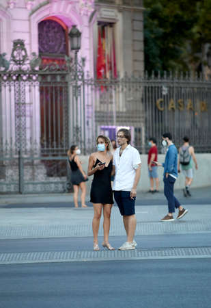 Madrid, Spain - August 8, 2020: Tourists and walkers walk through the city of in a sunset in the city of Madrid. People wear a mask to protect yourself from Covid-19のeditorial素材