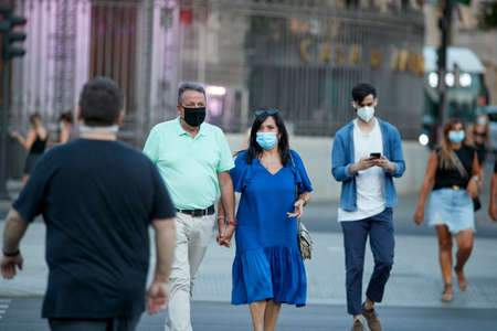 Madrid, Spain - August 8, 2020: Tourists and walkers walk through the city of in a sunset in the city of Madrid. People wear a mask to protect yourself from Covid-19のeditorial素材