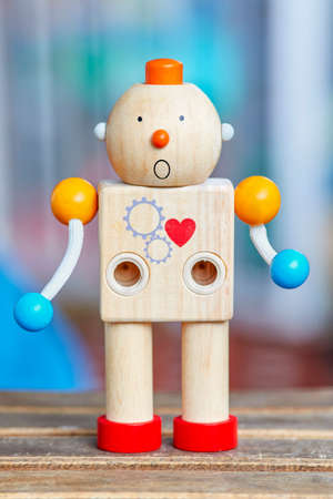 Wooden toy robot with red heart and surprise face. Defocused background.の写真素材