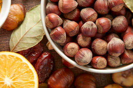 Various raw nuts: hazelnuts, pistachios, chestnuts, dates and oranges.の写真素材
