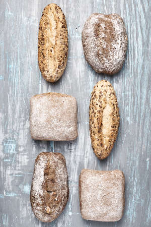From above shot of shabby surface with various bread loaves arranged in lines.