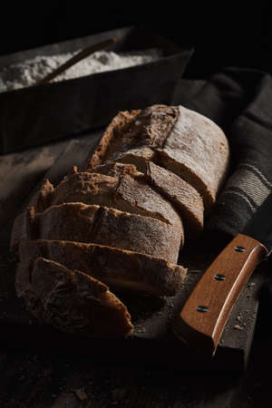 Arrangement of crispy bread cut in slices on wooden board in dark.の写真素材