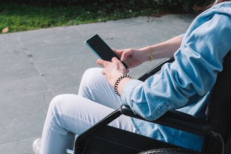 Disabled girl in a wheelchair using her mobile phone.Disable and technology conceptの写真素材