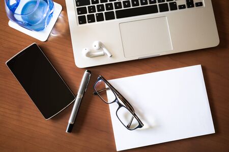 Laptop and smart phone located in young working woman's office desk with others supplies . Business...