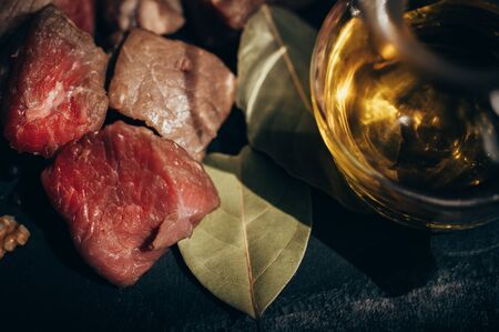 Still life of raw red beef together with some laurel leaves and olive oil gently illuminated by the sun. Concept of organic uncooked foodの写真素材