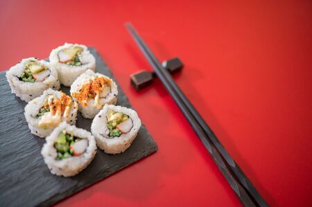 Japanese food,sushi set on blackboard and chopsticks isolated on red background. Copyspaceの写真素材