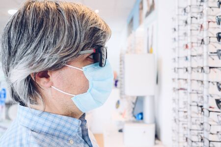 Man with flu mask wearing sunglasses at an eyewear store. Business, shopping and eye care conceptの写真素材