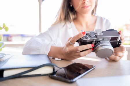 Pretty and successful blogger girl checks photos on her vintage camera.の写真素材