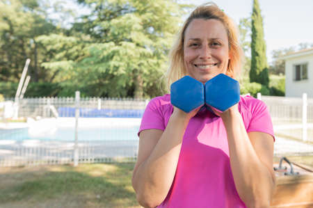 Nice woman holds dumbbells during her fitness sessions at home.Copy space. Sports and health...