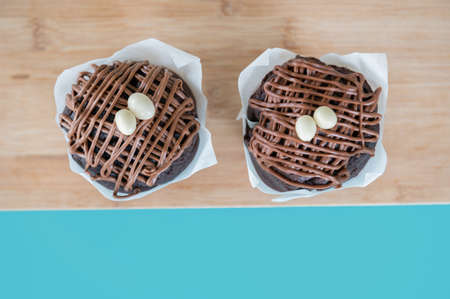 Two delicious homemade chocolate muffins on a wooden board on a turquoise background.Copy space....
