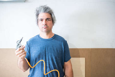 Middle-aged carpenter applies air pressure to hair.Copy spaceの写真素材