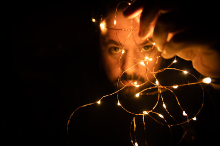 Man holds in his hand a Christmas garland. Selective focus. Isolated on black background.Copy space....