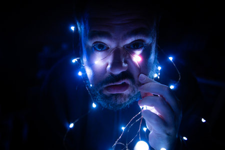 Portrait of a Caucasian man with a disgusting face illuminated by Christmas lights. Disgusting time...