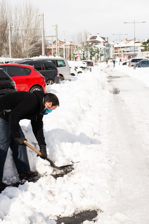 Volunteer man helps pick shovel snow so people can make cars to go to work.Adverse weather conditions.Copy spaceの写真素材