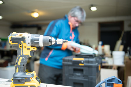 Drilling machine in wood workshop.Caucasian man in unfocused background.Professionals and tools...