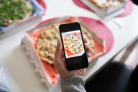 Blogger taking photo of tasty pizza with smart phone, closeup. Copy spaceの写真素材