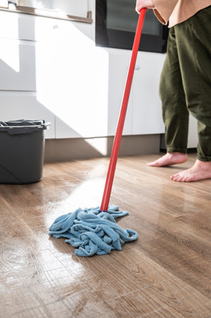 Close-up Of Person Cleaning Floor With Mop In Kitchen