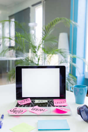 Notes with beautiful words of motivation on blank screen of laptop. Modern office with beautiful plants.の写真素材