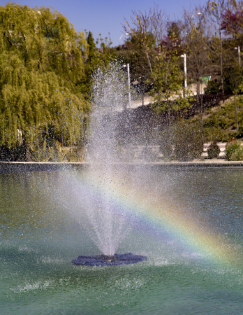 Rainbow on a fountain in a middle of a lakeの写真素材