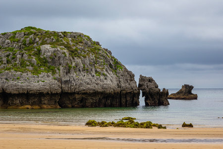 Some rocks on a beach with a cloudy sky, in Noja, Spainの写真素材