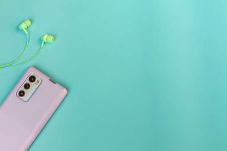 Green mobile phone case and headphones on a blue backgroundの写真素材