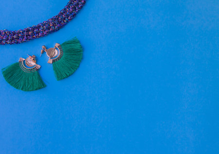 green earrings and purple necklace on blue backgroundの写真素材