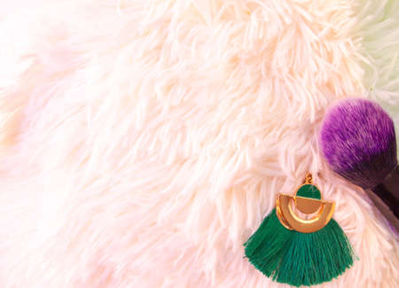 make-up brush and earring on a white fur backgroundの写真素材