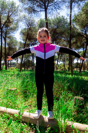 Child in tracksuit in front of a row of pinesの写真素材