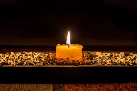 Candle in a dark room illuminating small stonesの写真素材