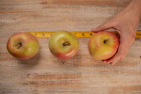 Apples surrounded by a tape measure and on weathered wood backgroundの写真素材
