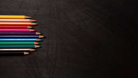 different color wooden pencils on black chalkboard background