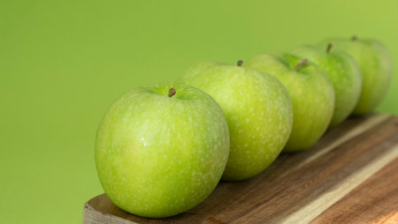 Green and fresh apples on wooden background and on green colorの写真素材