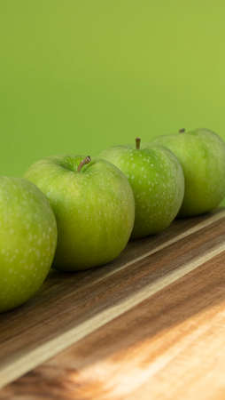 Green and fresh apples on wooden background and on green colorの写真素材