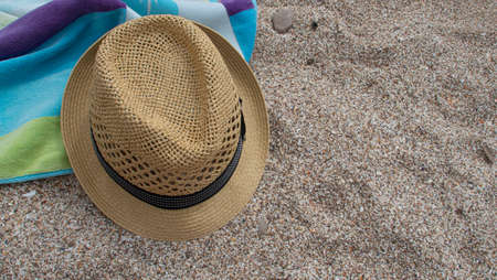 Yellow straw hat towel shade of blue and green colors on white sandの写真素材