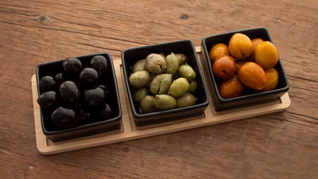 Different types of olives in three square black containersの写真素材