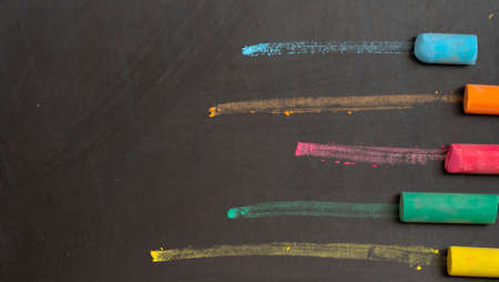 colored chalks on black chalkboard backgroundの写真素材