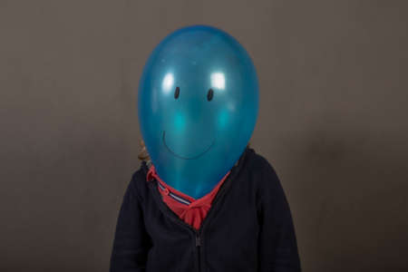 Painted blue balloon head with a happy face on a child's bodyの写真素材